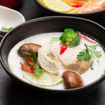 Tom Yum and Tom Kha traditional Thai soups with seafood, chicken, mushrooms, coconut milk and hot spices. With green tea pot and bowl